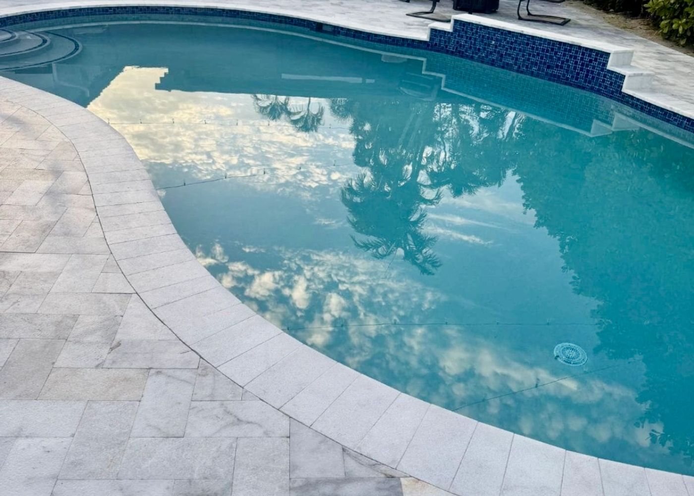 Ivory travertine pool deck and coping around a curved pool, an All Around Turf & Pavers project